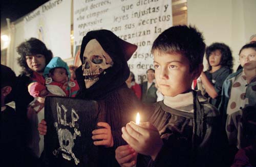 Adan Anguiano, 9, right, holds a candle next to a masked Jeffrey Arroyo, 9, in costume as Death, during a vigil in protest of Proposition 187 attended by 100 people at Dolores Mission Catholic Church in Los Angeles, Nov. 1, 1994.